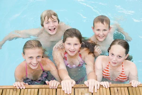 Vijf jonge vrienden in zwembad glimlachen — Stockfoto