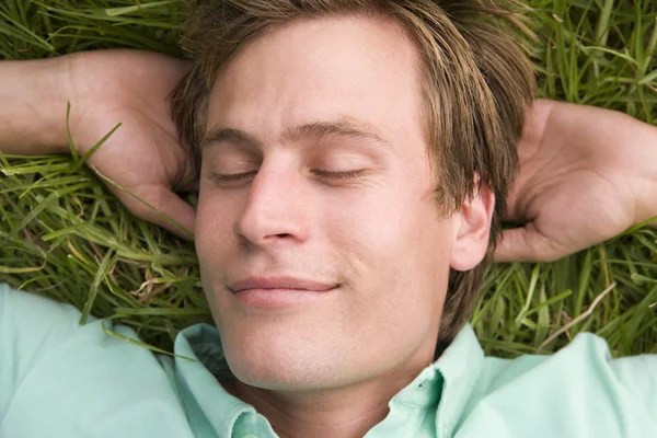 Mann liegt schlafend auf Gras Stockbild