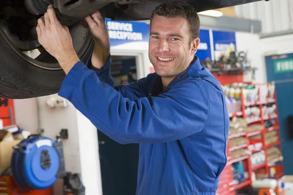 Mechaniker arbeitet unter Auto lächelnd Stockbild