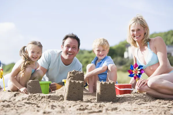 Familie op strand maken zandkastelen glimlachen — Stockfoto