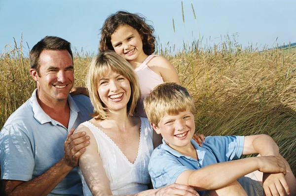 Family sitting outdoors smiling Stock Image