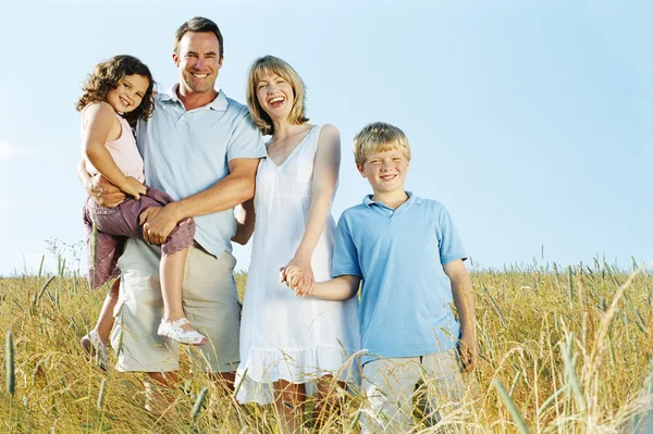 Family standing outdoors holding hands smiling Stock Photo