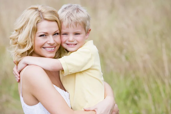 Mother holding son outdoors smiling Stock Picture