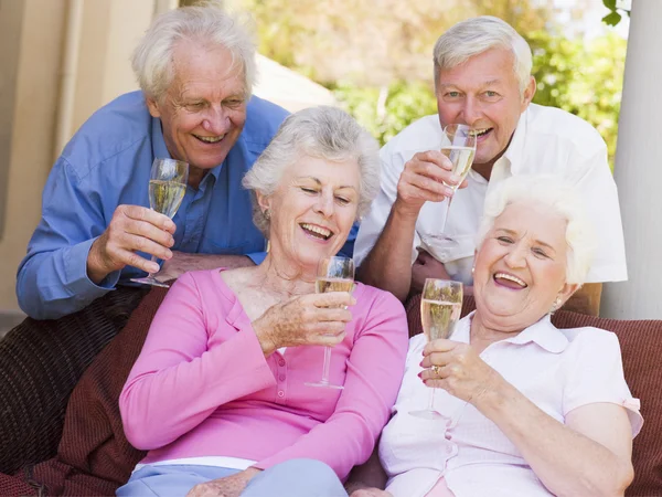 Two couples on patio drinking champagne and smiling — Stock Photo, Image