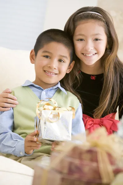 Bratr a sestra sedí na gauči, drží vánoční dárek Royalty Free Stock Fotografie