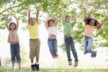 Five young friends jumping outdoors smiling clipart