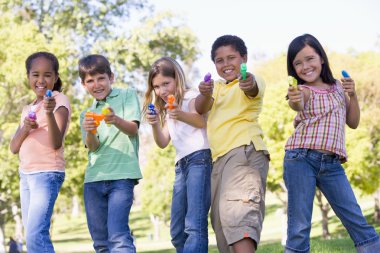 Five young friends with water guns outdoors smiling clipart