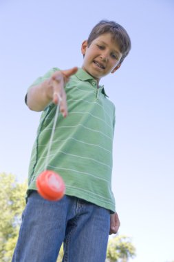 Young boy using yo yo outdoors smiling clipart