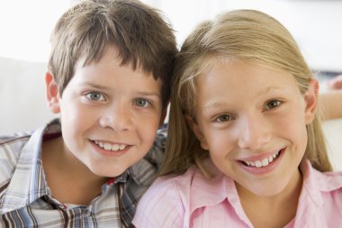 Brother And Sister Sitting Side By Side On A Couch clipart