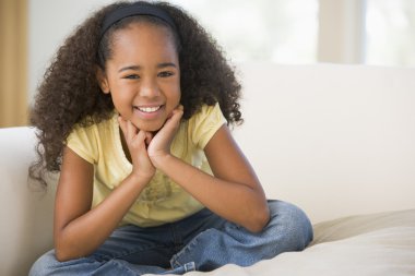 Young Girl Sitting Cross Legged On A Sofa At Home clipart