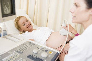 Pregnant woman getting ultrasound from doctor clipart