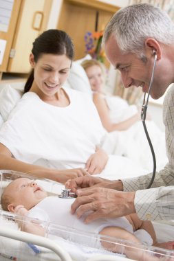 Doctor checking baby's heartbeat with new mother watching and sm clipart