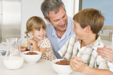 Father Sitting With Children As They Eat Breakfast clipart