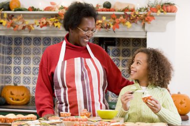 Grandmother and granddaughter making Halloween treats and smilin clipart