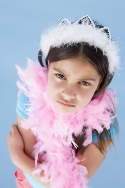 Young girl wearing crown and feather boa frowning clipart