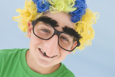 Young boy wearing clown wig and fake nose smiling clipart