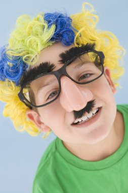 Young boy wearing clown wig and fake nose clipart