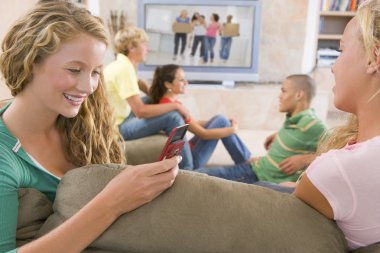 Teenagers Hanging Out In Front Of Television Using Mobile Phones clipart