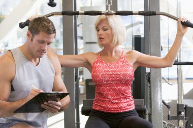 Personal Trainer Watching Woman Weight Train clipart