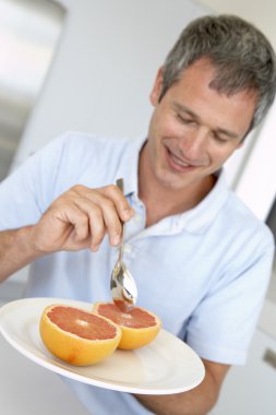 Middle Aged Man Eating Fresh Grapefruit clipart