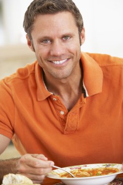 Middle Aged Man Eating Soup, Smiling At The Camera clipart