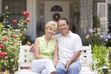 Couple Sitting On Bench Outside House clipart