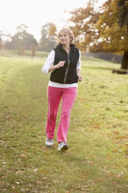 Senior Woman Power Walking In The Park clipart