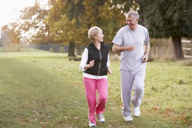 Senior Couple Power Walking In The Park clipart