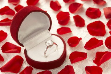 Diamond Ring In Heart Shaped Box Surrounded By Rose Petals clipart