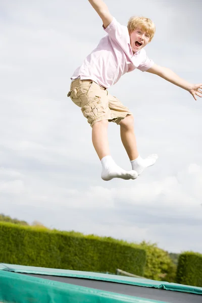 Mladý chlapec, skákání na trampolíně s úsměvem — Stock fotografie