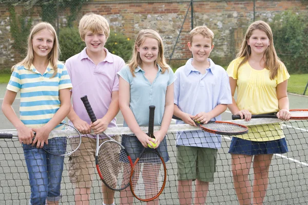 Fünf junge Freunde mit Schlägern auf dem Tennisplatz lächeln — Stockfoto