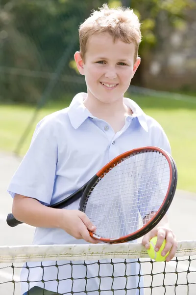 Мальчик с ракеткой на теннисном корте улыбается — стоковое фото
