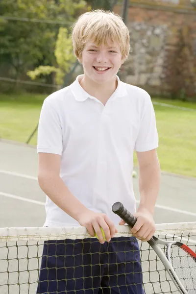 Niño con raqueta en pista de tenis sonriendo — Foto de Stock