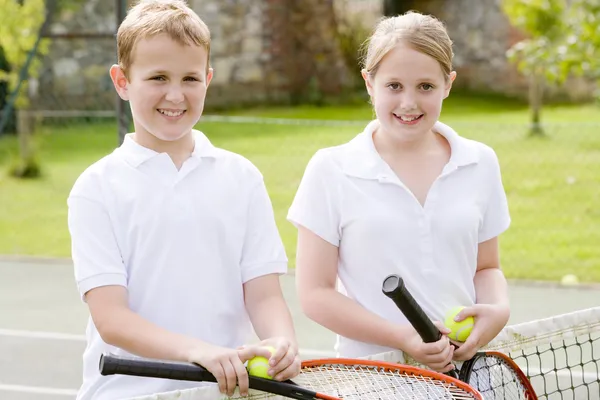 Dva mladí přátelé s raketami na tenisový kurt s úsměvem — Stock fotografie