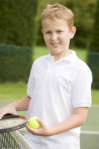 Young boy with racket on tennis court smiling — Stock Photo, Image