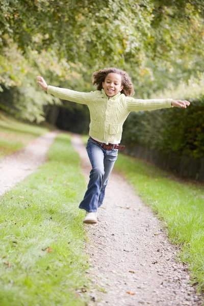 Young girl running on a path outdoors smiling — Stock Photo, Image