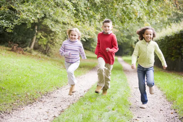 Three Young Friends Running Path Outdoors Smiling — Stock Photo, Image