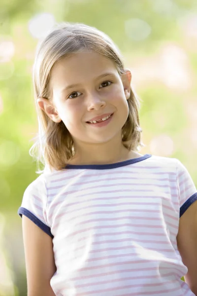 Jong meisje permanent buitenshuis glimlachen — Stockfoto