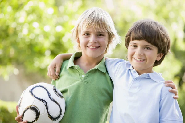 Two young boys outdoors with soccer ball smiling — Stock Photo, Image