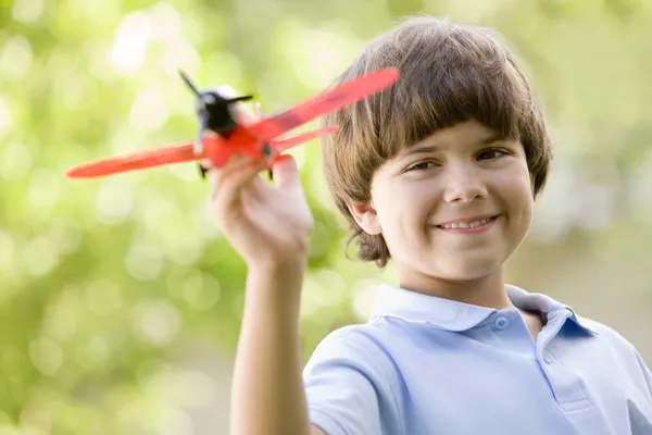Мальчик с игрушечным самолетом на открытом воздухе улыбается — стоковое фото