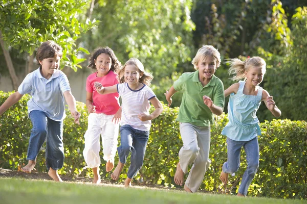 П'ять молодих друзів біжать на відкритому повітрі посміхаючись — стокове фото
