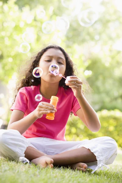 Chica joven soplando burbujas al aire libre — Foto de Stock