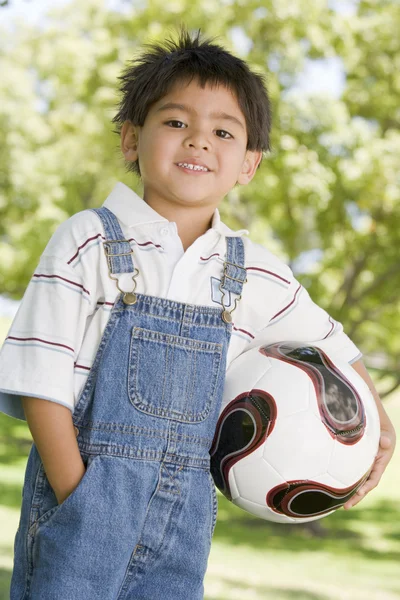 Young boy holding soccer ball outdoors smiling — Stock Photo, Image