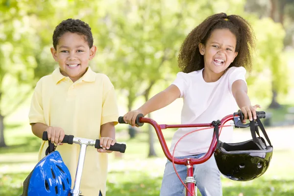 兄と妹屋外でスクーターや自転車笑顔で — ストック写真