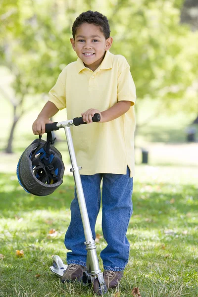 Ung pojke utomhus på skoter leende — Stockfoto