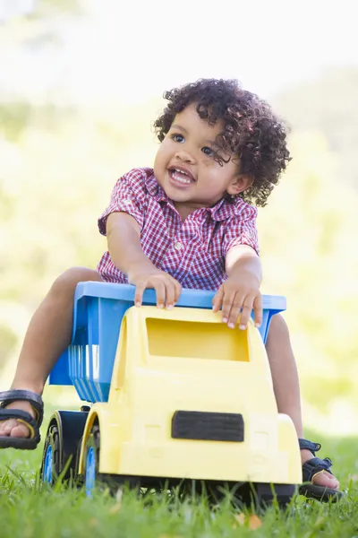 Joven niño jugando en juguete volcado camión al aire libre —  Fotos de Stock