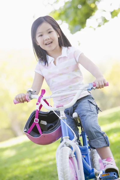 Jong meisje op fiets buitenshuis glimlachen — Stockfoto
