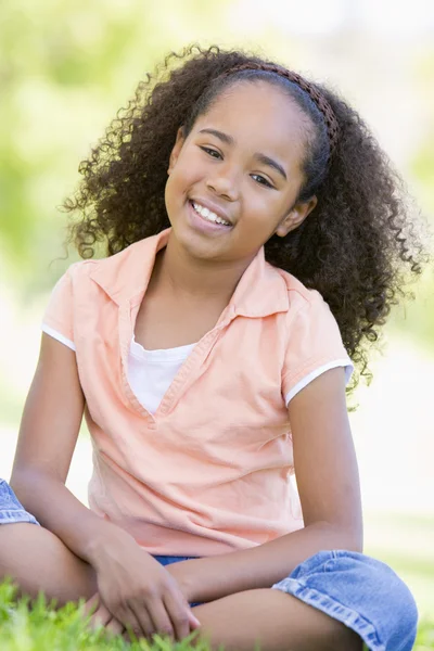 年轻的女孩坐在户外微笑 — 图库照片