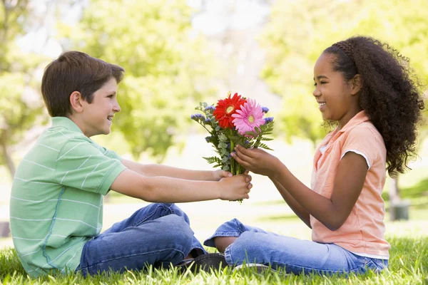 Junge Schenkt Jungen Mädchen Blumen Und Lächelt — Stockfoto