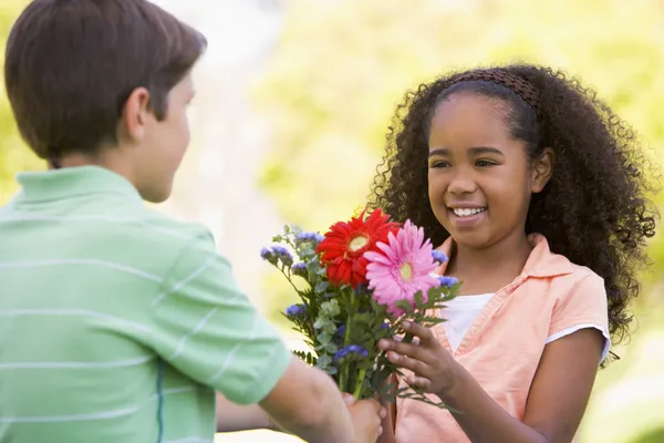 Mladý Chlapec Dává Mladé Dívce Květiny Usmívá — Stock fotografie